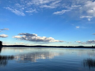 Obraz premium Tranquil Lake Reflections: Clouds Mirrored on the Water's Surface