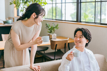 家のリビング・ソファで会話する仲良しの若い日本人夫婦
