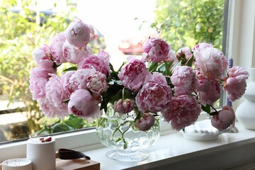 Beautiful pink peonies in vase on window sill. Interior design - obrazy, fototapety, plakaty