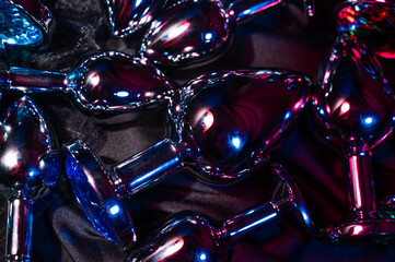 Lots of metal anal plugs in neon pink purple light. 