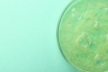 Petri dish with color liquid sample on light blue background, top view. Space for text