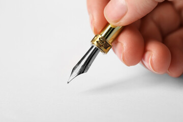 Woman with fountain pen above white paper, closeup