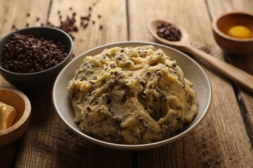 Chocolate chip cookie dough in bowl and ingredients on white wooden table, closeup