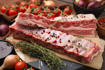 Raw pork ribs with thyme and peppercorns on table, closeup