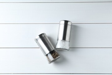 Salt and pepper shakers on white wooden table, flat lay