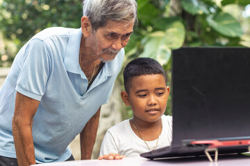 A young tech savvy Filipino boy teaches his grandfather how to use the laptop. Watching how to...