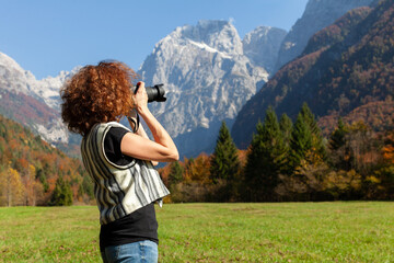 Mid Adult Curly Hair Woman Tourist Taking Photographs With a DSLR Reflex Camera in Mountains Beautiful Countryside - Side View