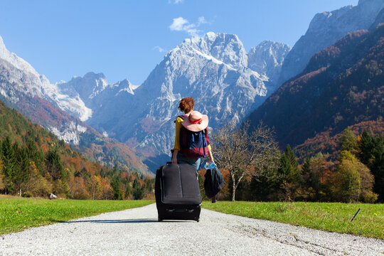 Adult Woman With a Big Rolling Suitcase Walking into a Beautiful Mountain Environment