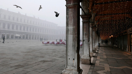 Venice in winter fog. Piazza San Marco, St Mark's Square, mostly empty apart from a few people,...