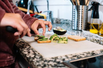 Young girl in the kitchen preparing avocado toasts. Detail