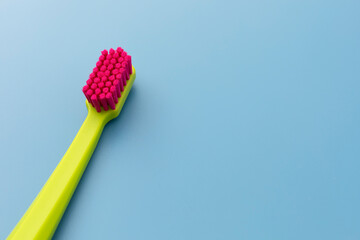 Flat Lay Mockup Green Toothbrush with Pink Bristles Lying On Blue Background, Copy Space For Tex....