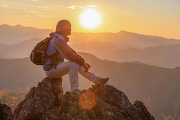 Hiker with backpack sitting on top mountain sunset background. Hiker man hiking living healthy active lifestyle.