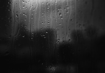 rain on window in background of city. Black and white toned image 