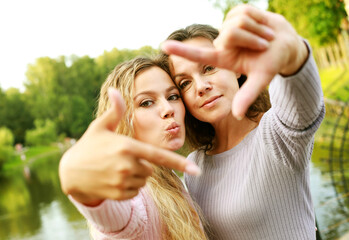Lifestyle, family and people concept: mature mother and adult daughter are doing selfie by mobile...