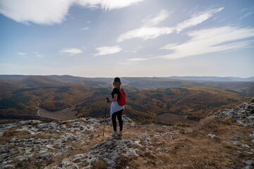 woman on mountain peak looking in beautiful mountain valley in autumn. Landscape with sporty young...