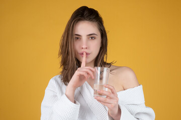 Woman drinking water, isolated on studio background. Portrait of young woman with glass of fresh water. Thirsty woman. Refreshing. Water balance. Portrait of woman drinking pure water.