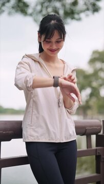 An Asian woman in workout attire is exercising with the smartwatch's fitness function in a public park. Capture the blend of technology and outdoor fitness for a vibrant image