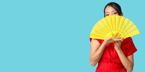 Beautiful Asian woman with fan and figurine of dragon on blue background with space for text....