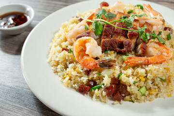 A closeup view of a plate of fried rice, featuring pork belly and shrimp.