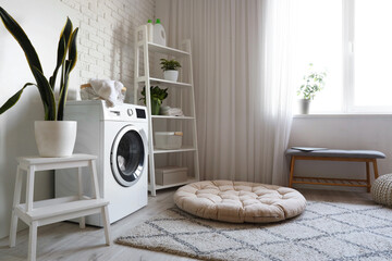 Interior of cozy laundry room with washing machine, shelving unit and bench