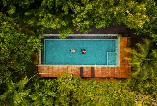 aerial drone view of swimming pool in the jungle of Krabi Thailand, aerial view with a drone above a swimming pool in the rainforest of Thailand. couple of men and women in pool during vacation - Powered by Adobe