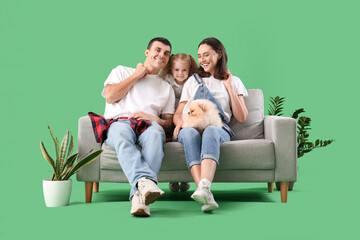 Happy family with dog sitting on sofa against green background