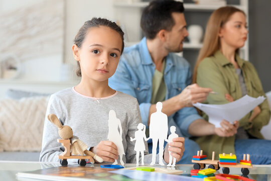 Sad little girl with family figure and her parents getting divorce at home