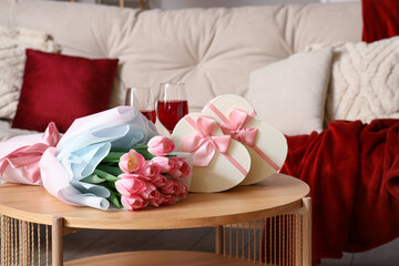 Roses with heart-shaped gift boxes and wine for Valentine's Day on table in living room, closeup