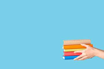 Hands holding books on blue background