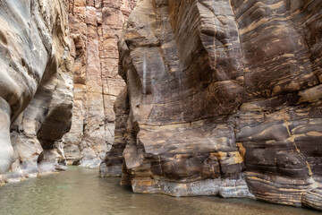 The shallow  Mujib River flows at start of the Mujib River Canyon hiking trail in Wadi Al Mujib in Jordan