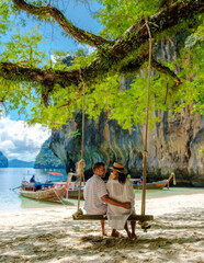 Koh Lao Lading Island near Koh Hong Krabi Thailand, is a beautiful beach with longtail boats, a couple of European men and an Asian woman on the beach. Couple on a boat trip in Krabi Thailand