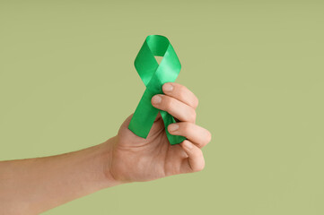 Young man with green ribbon on color background. Glaucoma awareness month