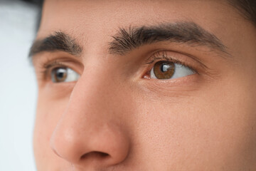 Young man with brown eyes on light background, closeup. Glaucoma awareness month