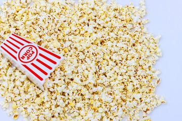 Popcorn box with white and red stripes and fluffy popcorn inside.