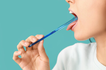 Young woman with tongue scraper on blue background - Powered by Adobe