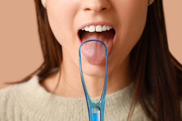 Young woman with tongue scraper on brown background