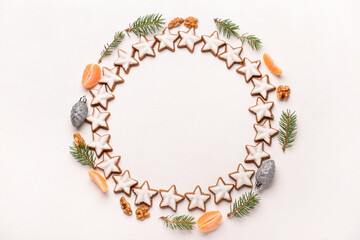 Frame made of delicious stars shaped Christmas cookies, mandarin and fir tree branches on light background