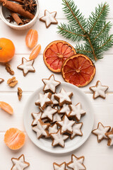 Composition with delicious stars shaped Christmas cookies, orange dried pieces, mandarins, spices and fir tree branch on light wooden background