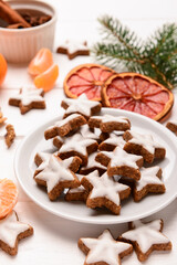 Plate with delicious stars shaped Christmas cookies on light wooden background, closeup