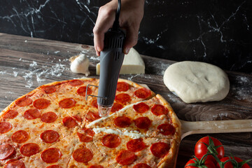 A view of a hand holding a heat gun over a cheesy part of the pizza.
