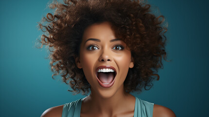 Curly haired young woman rejoicing. On teal background. 