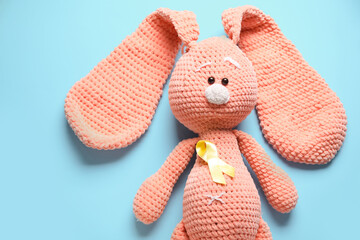 Toy bunny with golden ribbon on blue background. Childhood cancer awareness concept
