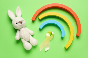 Golden ribbon with toys on green background. Childhood cancer awareness concept