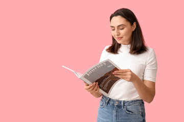 Beautiful young woman reading journey magazine on pink background