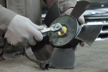 Repair and maintenance of the car at the service center. An auto mechanic replaces the impeller of...