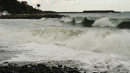 A view from the shore of a rough, muddy, stormy sea. Waves and foam on the shore during bad weather. The dirty Black Sea with big waves.