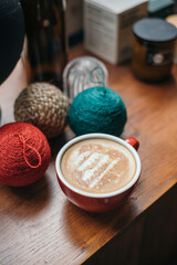 Christmas tree latte art in red coffee mug on rustic wooden table with decoration 