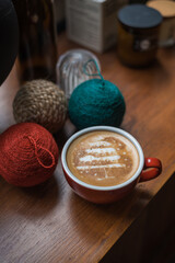 Christmas tree latte art in red coffee mug on rustic wooden table with decoration 
