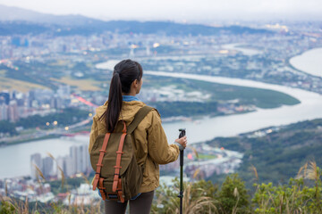 Hiking woman with trekking pole and stand on the top of mountain