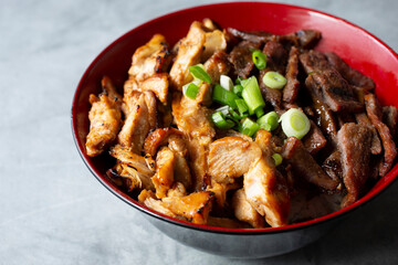 A closeup view of a teriyaki beef and chicken bowl.